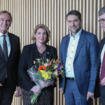 Mehrere Personen stehen nebeneinander, Claudia Kalisch hält einen Blumenstrauß in den Händen.