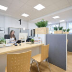 Eine Frau sitzt in einem Großraumbüro und arbeitet an einem Computer.