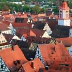Historischer Stadtkern aus der Vogelperspektive, man sieht rote Ziegeldächer, Fachwerkhäuser und eine Kirche.