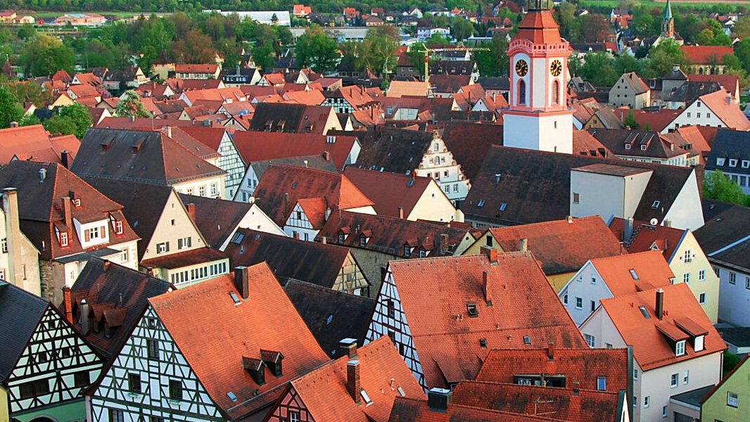 Historischer Stadtkern aus der Vogelperspektive, man sieht rote Ziegeldächer, Fachwerkhäuser und eine Kirche.