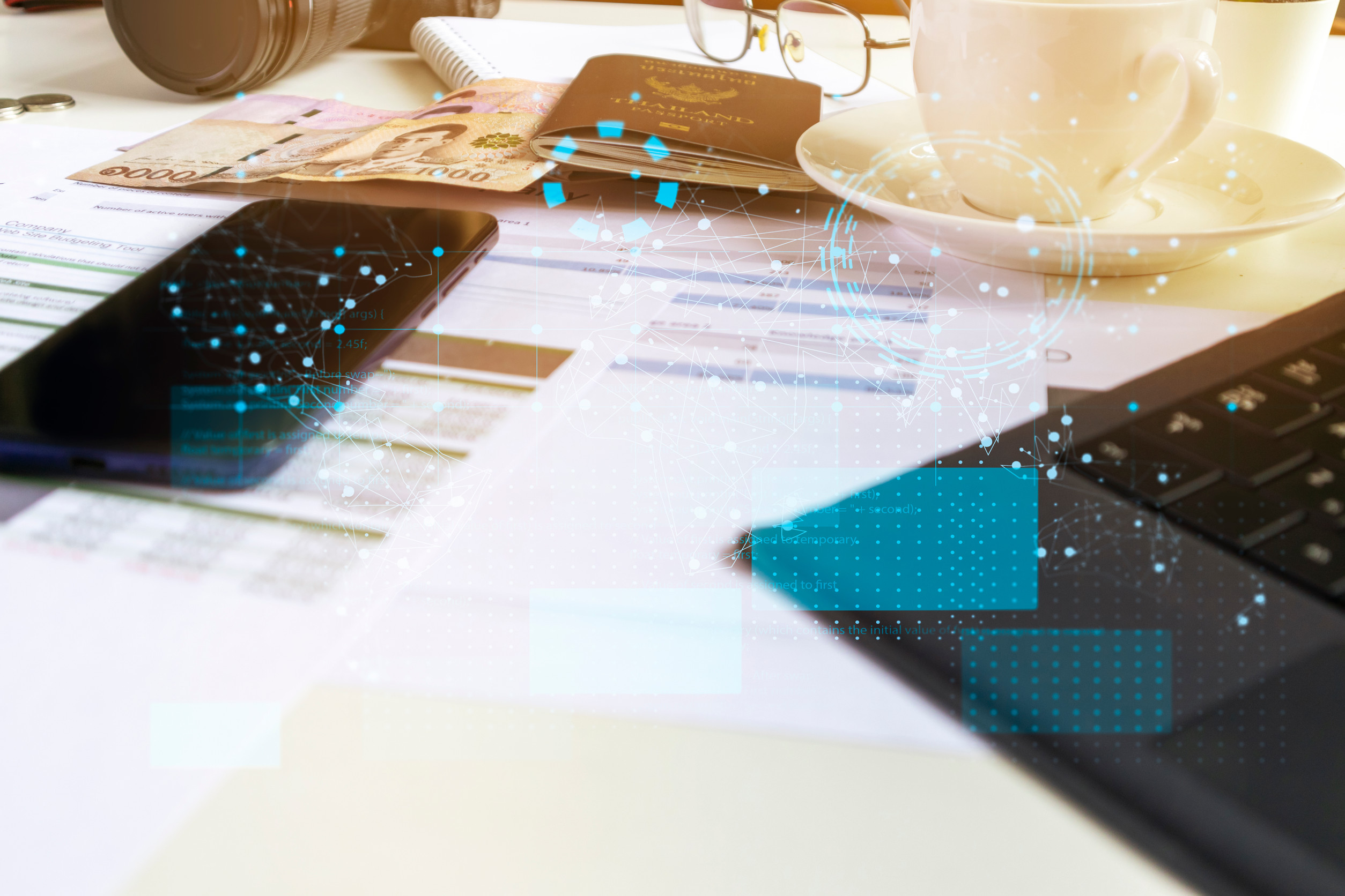 Auf einem Tisch liegen ein Smartphone und ein papierbasierter Antrag zwischen einem Laptop und anderen Utensilien auf einem Tisch.