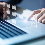 Eine Person tippt auf einer Computertastatur, über der Symbole für Dokumente und digitale Ordner schweben.