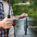 Angler hält eine Forelle in der Hand