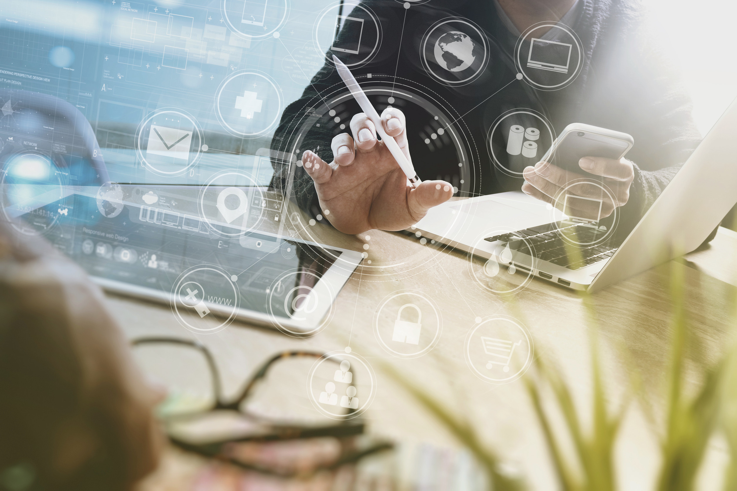 Montage: Schreibtisch, Laptops, Hände von Jacketttragenden Männern, Überlagerung mit diversen IT-Icons