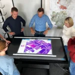 Mehrere Personen stehen um einen Datentisch versammelt, auf dem ein Stadtplan zu sehen ist.