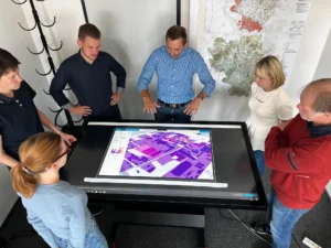 Mehrere Personen stehen um einen Datentisch versammelt, auf dem ein Stadtplan zu sehen ist.