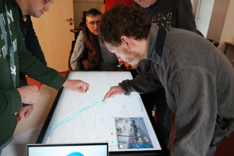 Mehrere Personen stehen um einen Maptable versammelt und bearbeiten eine Stadtkarte.