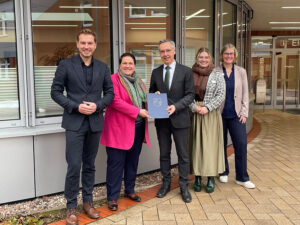 Mehrere Personen stehen nebeneinander und präsentieren den Förderbescheid für den Heidekreis.