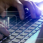 Eine Person arbeitet an einem Laptop mit Diagrammen.