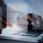 Eine Person arbeitet an einem Laptop über dessen Tastatur Dokumente schweben.