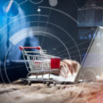 Nahaufnahme einer Person mit Einkaufswagen über einem Laptop.