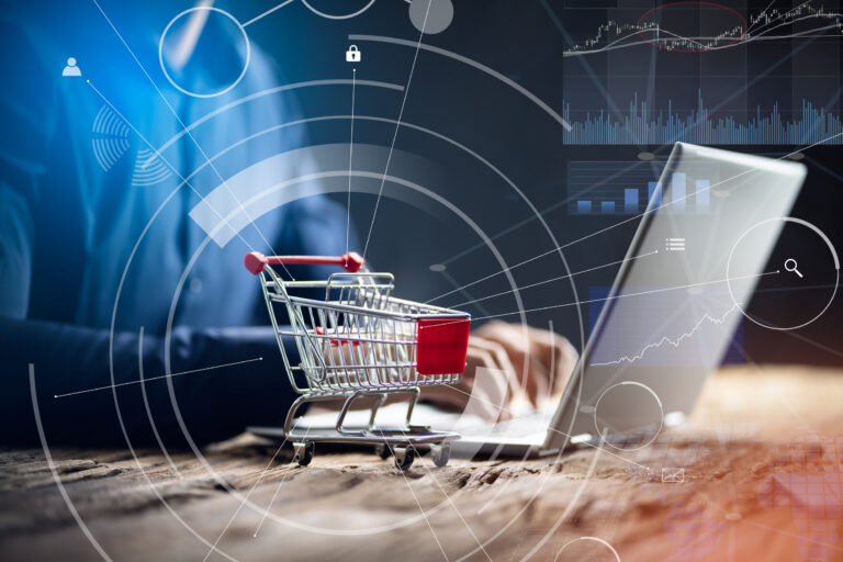 Nahaufnahme einer Person mit Einkaufswagen über einem Laptop.