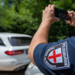 Eine bei der Polizeibehörde Freiburg um Breisgau angestellte Person nimmt mit der Smartphonekamera ein geparktes Fahrzeug auf.