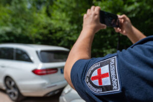 Eine bei der Polizeibehörde Freiburg um Breisgau angestellte Person nimmt mit der Smartphonekamera ein geparktes Fahrzeug auf.