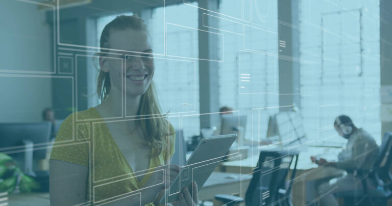 Eine lächelnde Frau hält ein Tablet in der Hand, im Hintergrund ist ein Großraumbüro zu sehen.