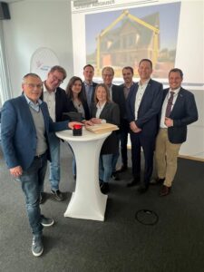 Mehrere Personen stehen um einen Tisch mit einem Startknopf versammelt.