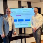 Vier Personen stehen um einen Monitor versammelt, auf dem das Smart City Dashboard für Schlangen zu sehen ist.