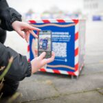 Eine Person scannt mit dem Smartphone den QR-Code eines Stadtwürfels in Bremerhaven.