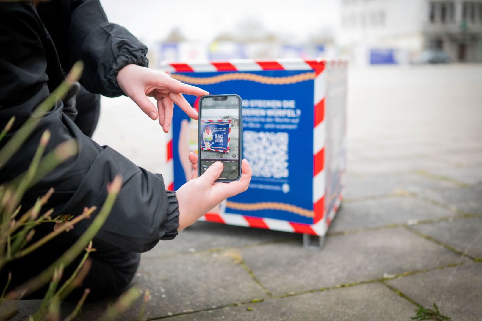 Eine Person scannt mit dem Smartphone den QR-Code eines Stadtwürfels in Bremerhaven.
