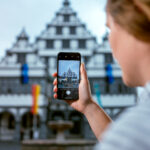 Eine junge Frau macht per Smartphone ein Foto vom Potsdamer Rathaus.