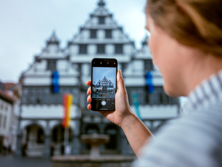 Eine junge Frau macht per Smartphone ein Foto vom Potsdamer Rathaus.