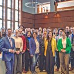 Mehrere Personen stehen in einem Raum zum Gruppenfoto versammelt.