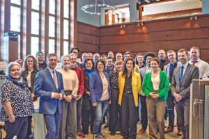 Mehrere Personen stehen in einem Raum zum Gruppenfoto versammelt.