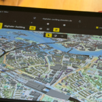 Der Digitale Zwilling der Stadt Dresden ist auf einem Tablet zu sehen, das eine Person in den Händen hält.