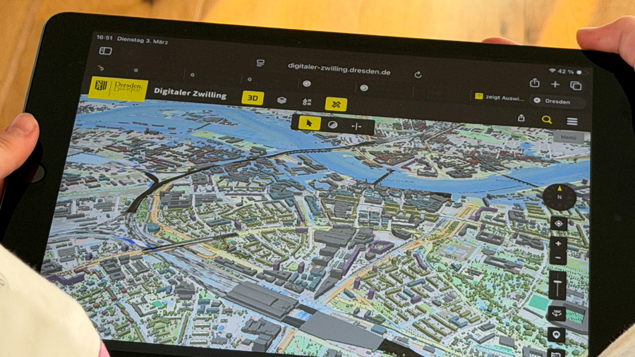 Der Digitale Zwilling der Stadt Dresden ist auf einem Tablet zu sehen, das eine Person in den Händen hält.