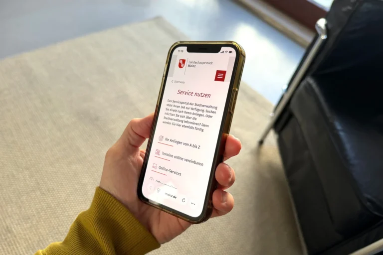 Hand hält Handy mit Website der Stadt Mainz, Relaunch