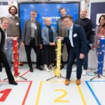 Mehrere Personen stehen vor einem digitalen Monitor versammelt, auf dem der Aachener Konzept-O-Mat präsentiert wird.