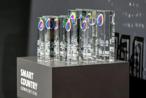 Transparente, kubische Trophäen stehen aufgereiht auf einem grauen Podest.