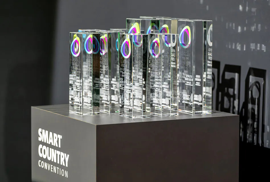 Transparente, kubische Trophäen stehen aufgereiht auf einem grauen Podest.