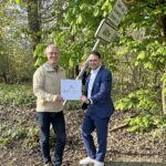 zwei Personen vor einem verbogenen Verkehrsschild