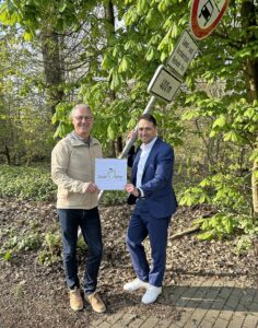 zwei Personen vor einem verbogenen Verkehrsschild