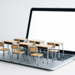 auf einem stilisierten Laptop stehen Schultische und -bänke