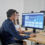 Zwei Personen sitzen vor einem Bildschirm auf dem die SMARD-Gov-Plattform zu sehen ist