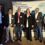 mehrere Personen stehen vor einer Leinwand mit einer Präsentation des Projekts SAP4HANA Wiesbaden