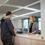 Person am Schalter schaut eine Mitarbeiterin an