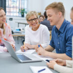 Team aus vier Personen sitzt an einem Tisch und tauischt sich aus.