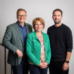 drei Personen vor grauem Hintergrund