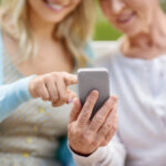 Tochter und Mutter im Seniorenalter im Park mit Smartphone