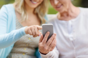 Tochter und Mutter im Seniorenalter im Park mit Smartphone