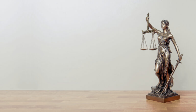 Justizia-Staue auf einem Tisch, heller Hintergrund