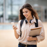 Asiatisch aussehende junge Studentin mit Smartphone in der Hand