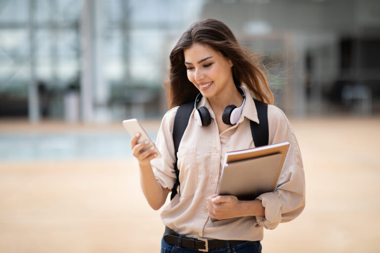 Asiatisch aussehende junge Studentin mit Smartphone in der Hand