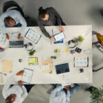 Sicht von oben auf Geschäftsleute die an einem Tisch zu einem Meeting versammelt sind