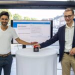 2 Männer vor Bildschirm, die einen Startknopf drücken_KI_Chatbot_INGO-gestartet