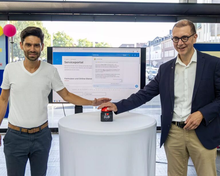 2 Männer vor Bildschirm, die einen Startknopf drücken_KI_Chatbot_INGO-gestartet