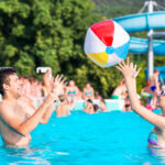 Ein junges Paar spielt mit Wasserball in einem Freibad
